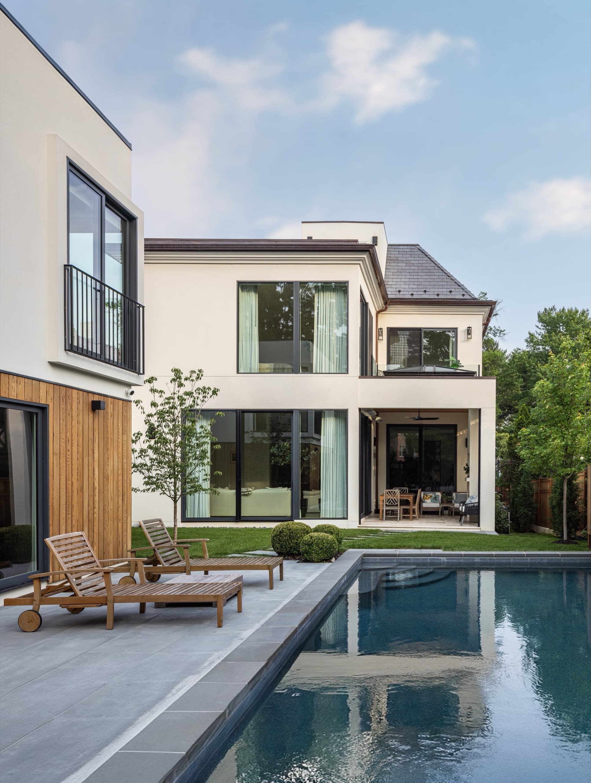 Modern rear elevation and pool terrace, with teak loungers on a stone deck