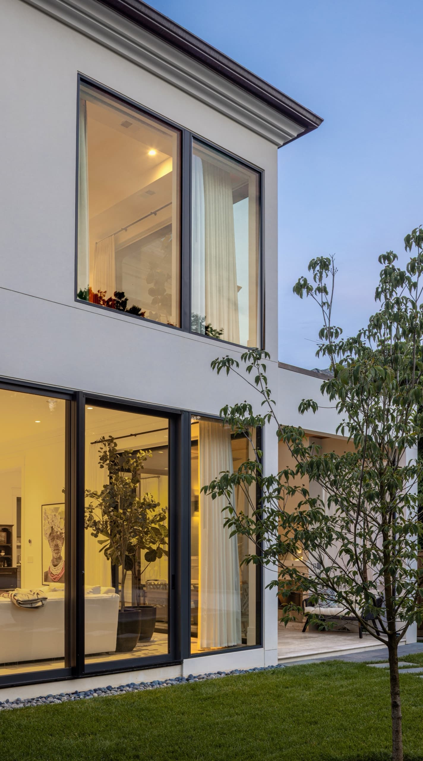 Full-height corner glazing on the rear elevation, framed by young garden planting — Observatory Circle, Northwest Washington, D.C.